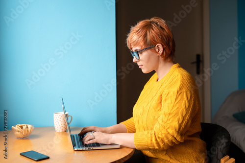 Young blond woman using her laptop at home photo