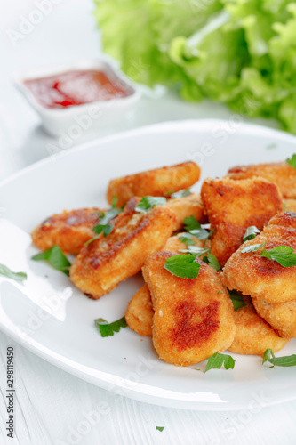 Fried chicken nuggets with ketchup sprinkled with chopped parsley.