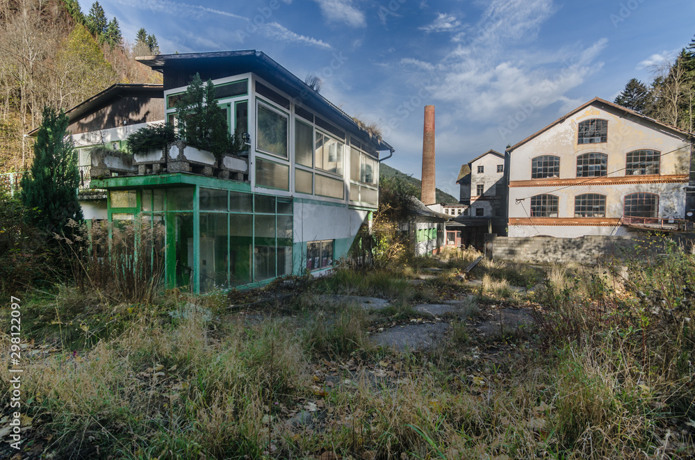 verwachsene gebaeude einer fabrik im gebirge