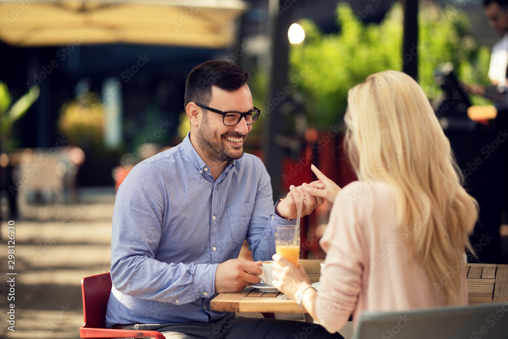 Happy man talking to his girlfriend while holding her hand in a cafe. Happy man talking to his girlfriend while holding her hand in a cafe.