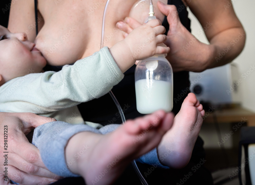 Mother Pumps Milk While Breastfeeding Her Baby Mother Pumps Milk While Breastfeeding Her Baby