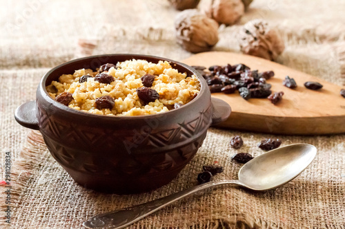 Sweet millet porridge with dark raisins in ceramic rustic bowl