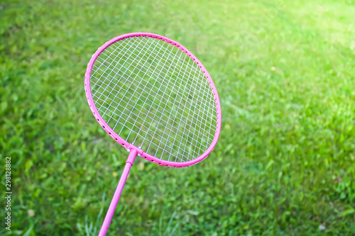 Badminton racket on green summer grass background close up