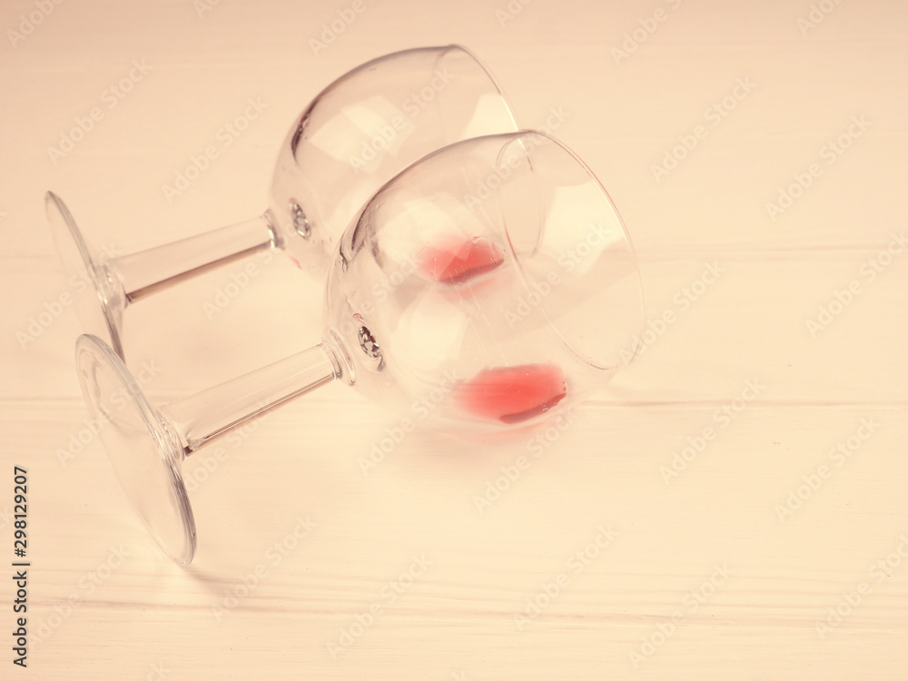 two glasses with the remains of wine lie on a white wooden background, a copy of the space