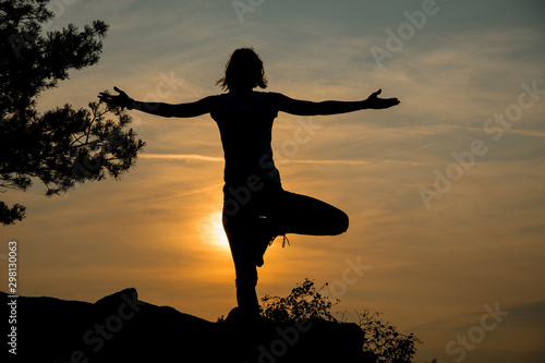 Young woman exercising yoga at dawn against sun  outdoor peace