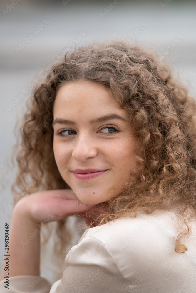 Cheerful young woman with curly hair resting her head on her hand Cheerful young woman with curly hair resting her head on her hand