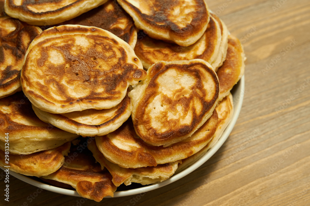 Stack of delicious homemade pancakes on plate, wooden table as background