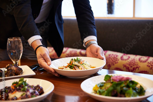 Waiter Placing Food On Table At Restaurant