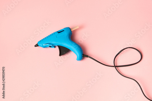 New blue glue gun for handcraft working on a color of the year 2019 Living Coral pantone background, copy space.
