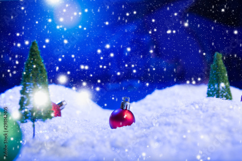 Christmas background with Christmas balls on snow over fir-tree  night sky and moon. Shallow depth of field. Christmas background. Fairy tale. Macro. Artificial magic dreamy world.