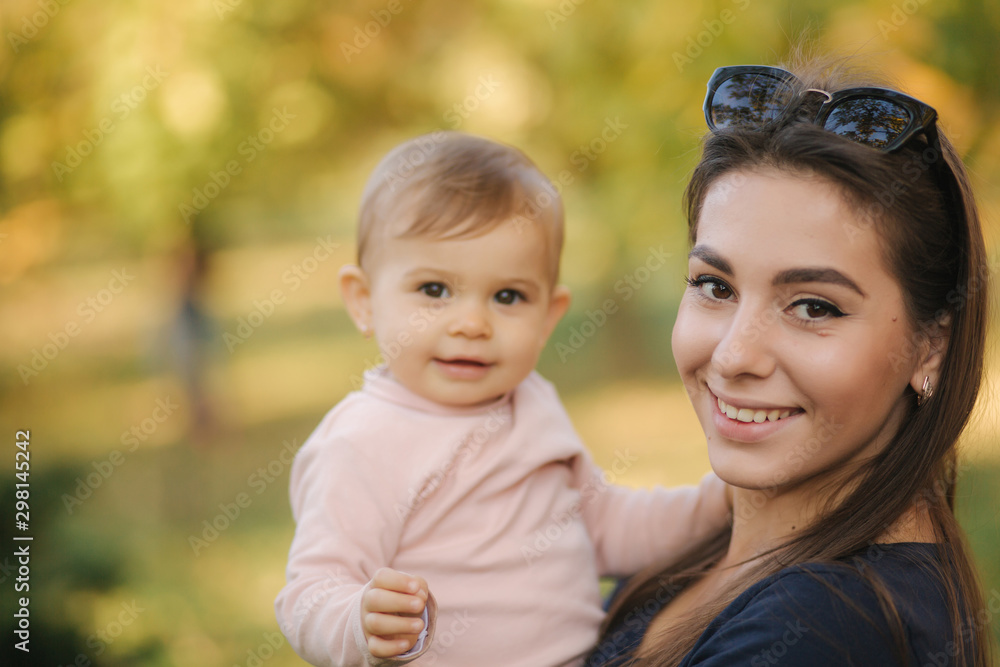 Portrait of beautiful family in the park. Mom and daughter togehter in autumn. Beautiful ten month baby on mother's hands Portrait of beautiful family in the park. Mom and daughter togehter in autumn. Beautiful ten month baby on mother's hands