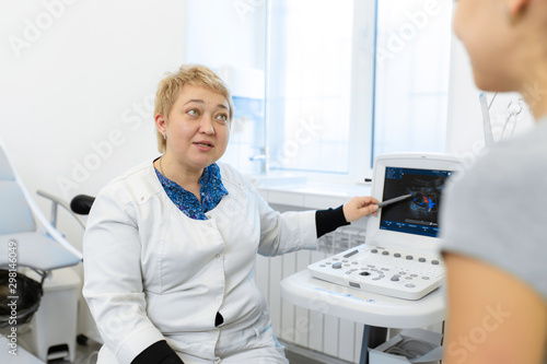 the doctor advises the patient's girl after an ultrasound diagnosis. indicates with a pen on the monitor of the ultrasound machine the problematic place to which the patient should pay special attenti photo