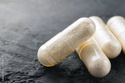 White medical capsules of glucosamine chondroitin, healthy supplement pills on dark background, macro image