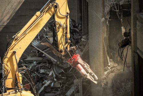 Heavy machinery surrounded with dust  cloud taking down an old building 