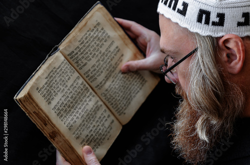 A Hasidic Jew reads Siddur. Religious orthodox Jew with a red beard and with pace in a white bale praying. On the bale is an inscription Rabbi Nahman from Uman. Closeup