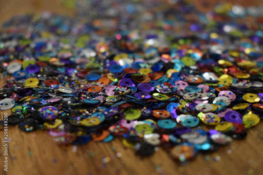 Pile of Glitter and sequins on brown wood table.