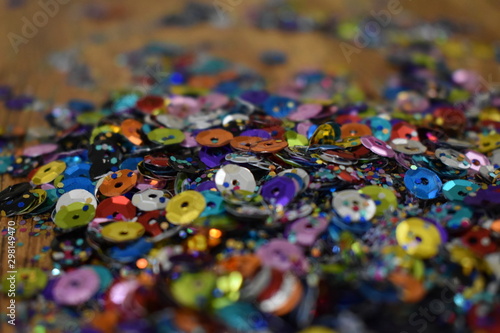 Pile of Glitter and sequins on brown wood table.