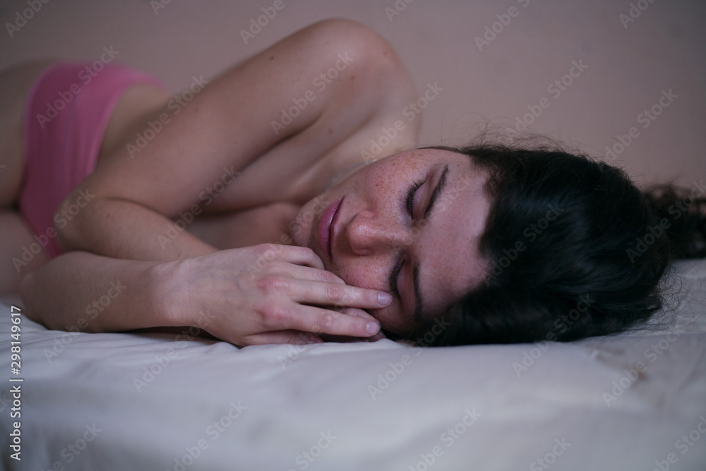sad girl portrait with freckles without clothes on a bed with loose black hair sad girl portrait with freckles without clothes on a bed with loose black hair