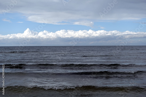 Dark cold waves of the Baltic Sea in the Gulf of Riga in Jurmala with layer of white clouds on skyline on a overcast windy day