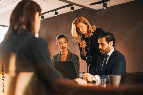 Mature female professional discussing with lawyers at office photo