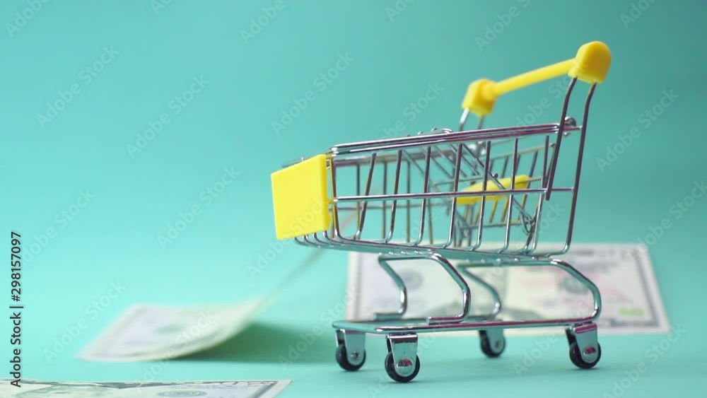 A mini basket on a blue background, dollars and money are falling and pouring into it from the top. A mini basket on a blue background, dollars and money are falling and pouring into it from the top.