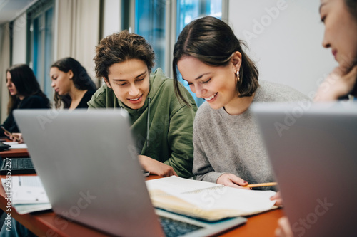 Smiling teenage students studying at desk in school photo