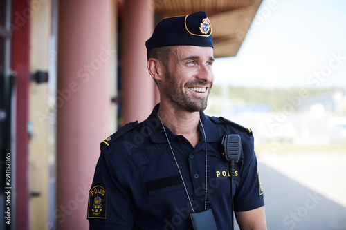 Happy policeman looking away while standing outside police station photo