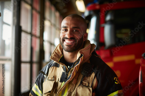 Portrait of smiling male firefighter in uniform at fire station photo