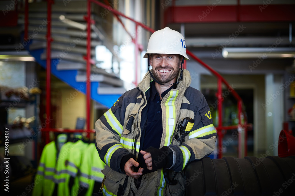 Portrait of smiling firefighter wearing protective suit at fire station Portrait of smiling firefighter wearing protective suit at fire station