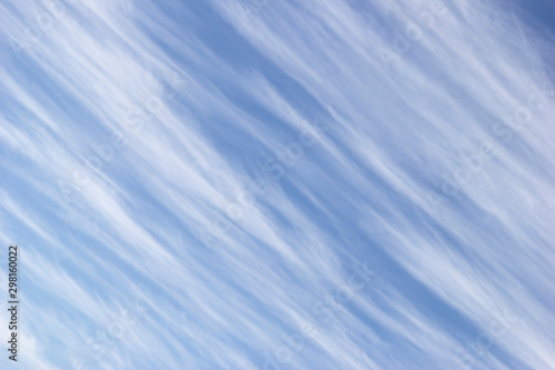 White cirrus clouds in the form of diagonal stripes on the background blue sky.