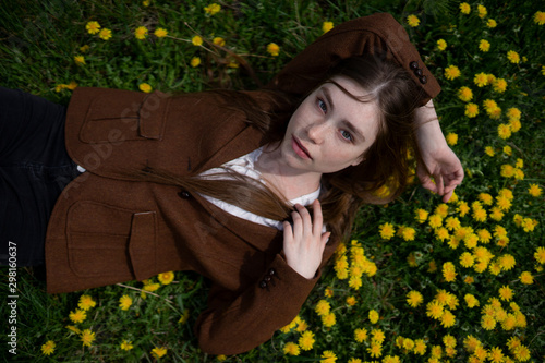 Young woman wearing brown blazer lying on yellow flowers photo