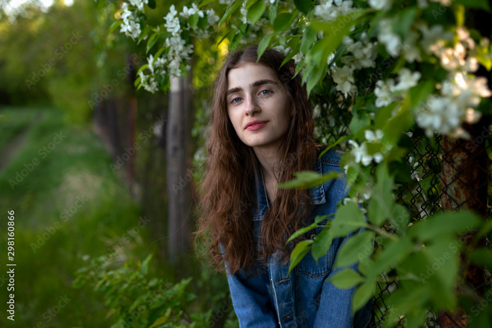 Young woman wearing denim jacket by white flowers Young woman wearing denim jacket by white flowers