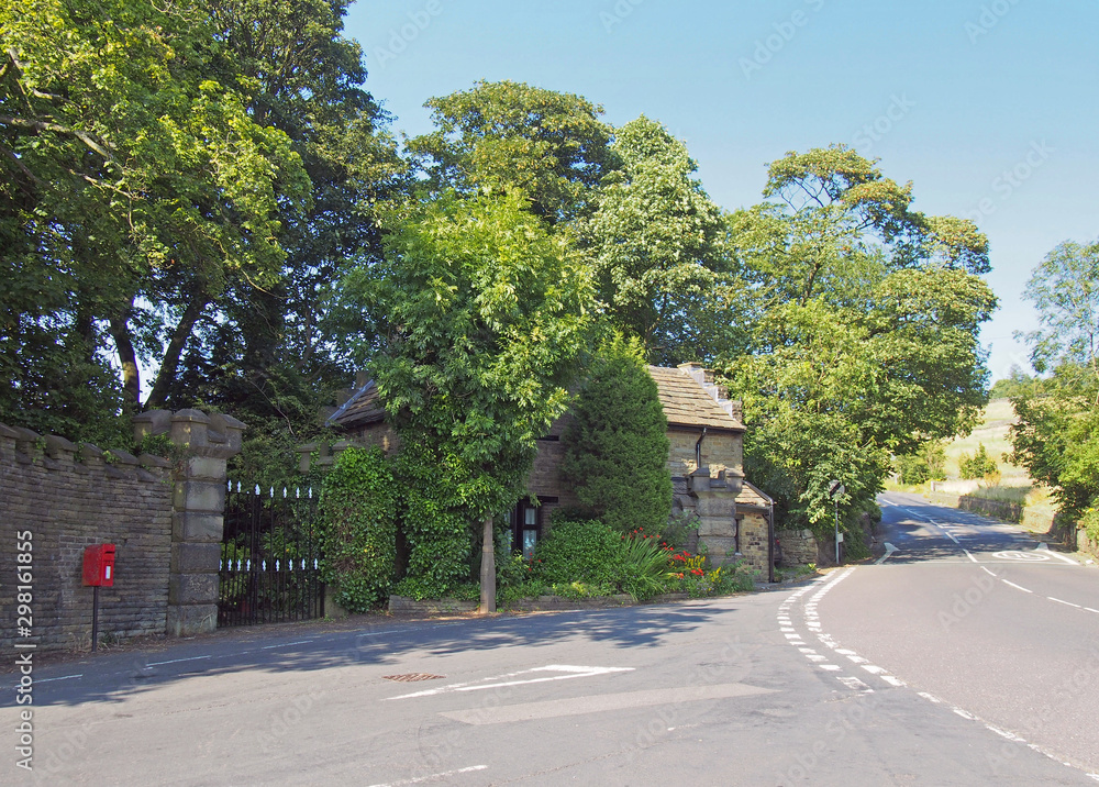 a roadside view of houses and trees in the small west yorkshire village of wortley in calderdale in summer sunlight