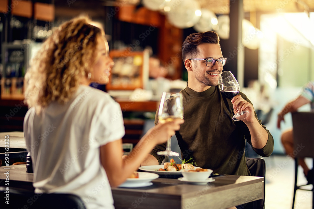 Young couple enjoying in glass of wine during a lunch.