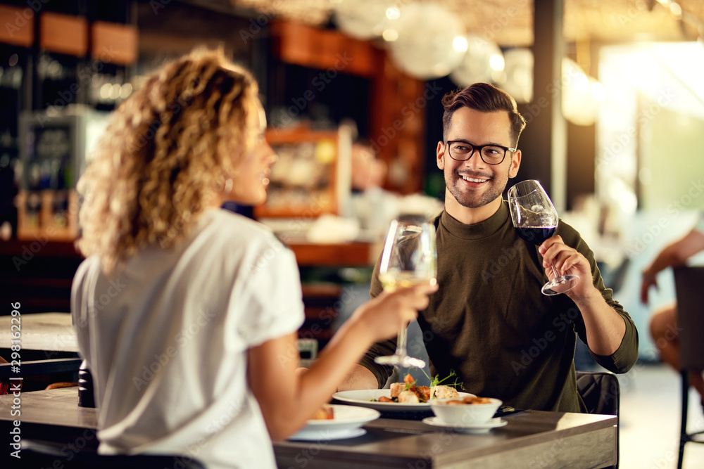 Happy man drinking wine and talking to his girlfriend in a restaurant.