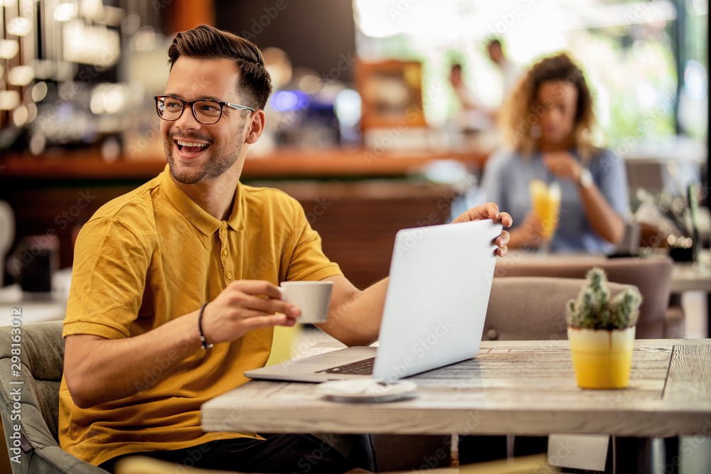 Cheerful man having fun while using laptop in a cafe. Cheerful man having fun while using laptop in a cafe.