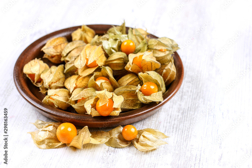 Physalis on a clay dish. Ripe berries of autumn physalis fruit Physalis on a clay dish. Ripe berries of autumn physalis fruit