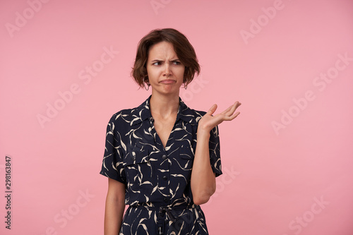 Foto Dissatisfied young brunette woman with short haircut standing over pink backgrou