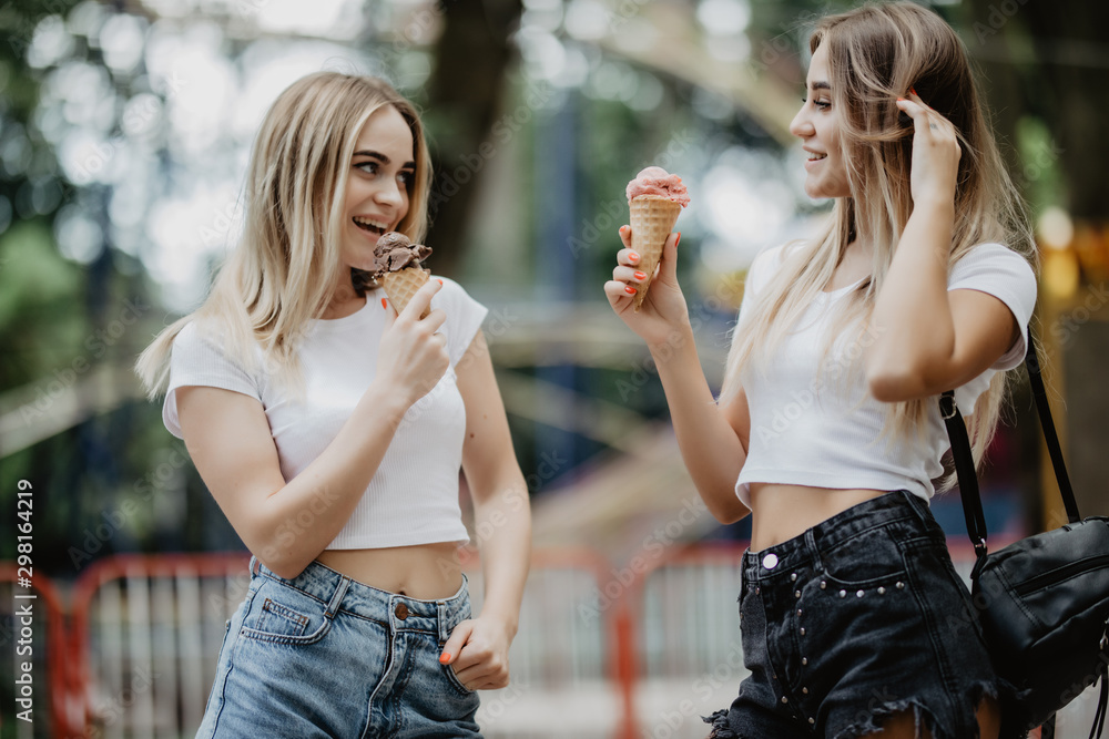 Portrait of two girls in glasses licking ice cream in city park Portrait of two girls in glasses licking ice cream in city park