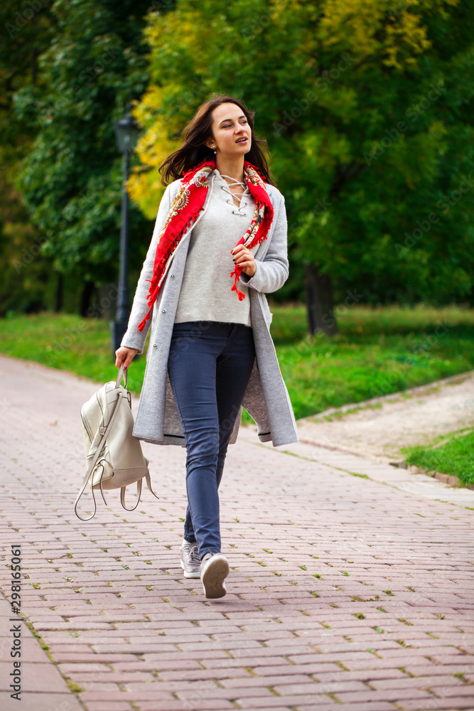 Obraz premium Portrait of a young beautiful girl in blue jeans and gray coat
