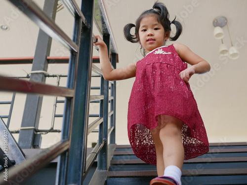 Photo Little baby girl, 42 months old, walking down the stairs by herself, holding on