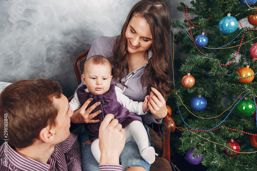 Cute family have fun in decorating room. Beautiful mother with little children and husband. Family near Christmas tree