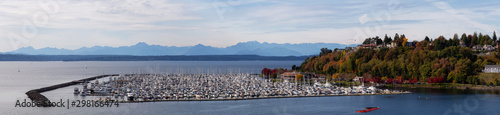 Beautiful Aerial Panoramic View of boats in a Marina on the Ocean Shore during a cloudy autumn evening. Taken in Smith Cove Park, Seattle, Washington, United States.