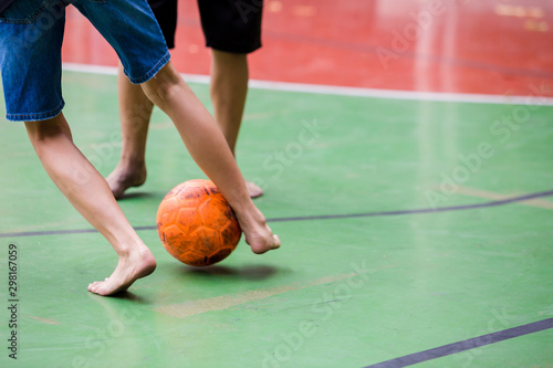 Futsal players barefoot. Futsal player  control and shoot ball to goal. Soccer players fighting each other by kicking the ball. Indoor soccer sports hall. Football futsal player, Orange ball.