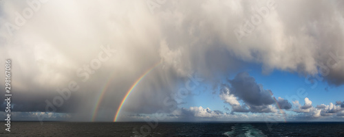 Dramatic Panoramic View of a cloudscape during a rainy and colorful morning with a bright double Rainbow. Taken over the Pacific Ocean in Alaska, USA. © edb3_16