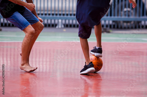 Futsal players between barefoot and sport shoes. Soccer players fighting each other by kicking the ball. Indoor soccer sports hall. Concept of inequality.