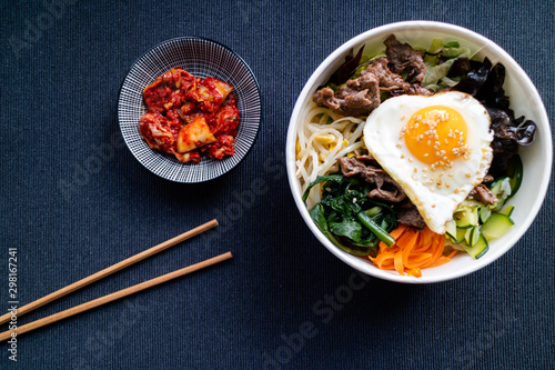 Bi bim bap with beef and kimchi on dark background. Korean cuisine. Top view.
