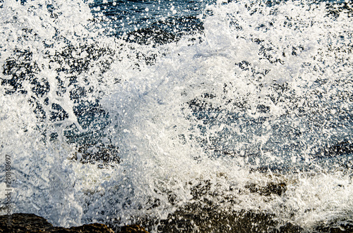A wave breaks on a rock on a sunny day. © YUABOG