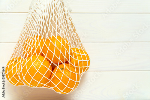 Oranges in a white mesh reusable bag