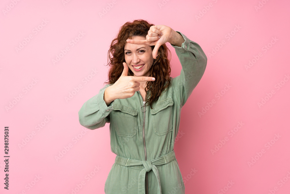 Young pretty woman over isolated pink background focusing face. Framing symbol Young pretty woman over isolated pink background focusing face. Framing symbol